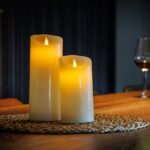 Uppladdningsbara LED-vaxljus från DORSETTO på träbord med glas vin och mjuk bakgrundsbelysning för en inbjudande atmosfär